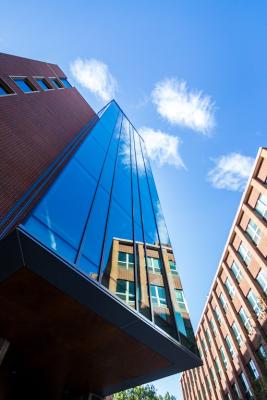 Colored photo showing Arrupe Hall's glass facade with a reflection of the Reiss Science Building. 