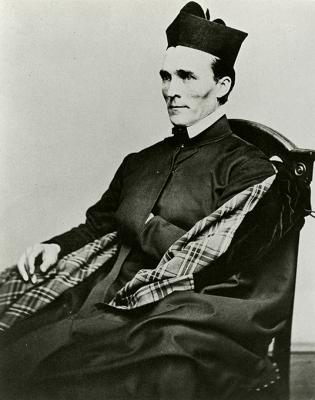 Black and white image showing Fr. Bernard A. Maguire seated for a portrait wearing his Jesuit robes and biretta.