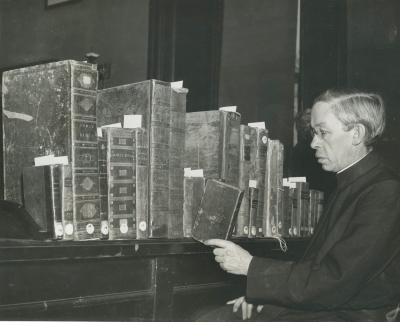 Photo of Father Wilfrid Parson S.J. picking a book from Riggs' bible collection