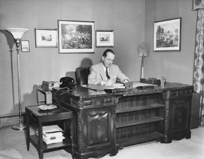 Photograph of James S. Ruby working at a desk in the Alumni House