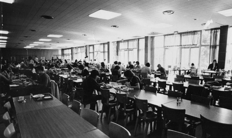 Black and white image of New South cafeteria in 1972 showing students dining family style at long tables. 