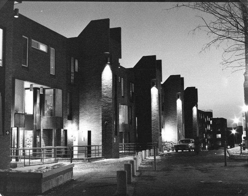 Black and white image of Village A in 1982 showing the Library Walk side of the apartment complex with the stairwells and sidewalks lit up at night. 