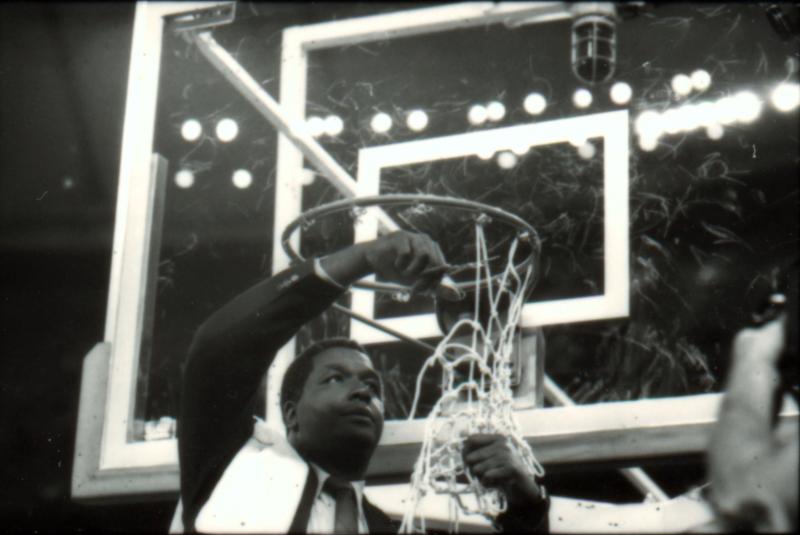 Image of men's basketball coach John Thompson Jr. celebrating Georgetown's 1984 championship by cutting down the nets